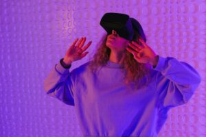 A woman using a VR headset, exploring a virtual world indoors with dynamic lighting.